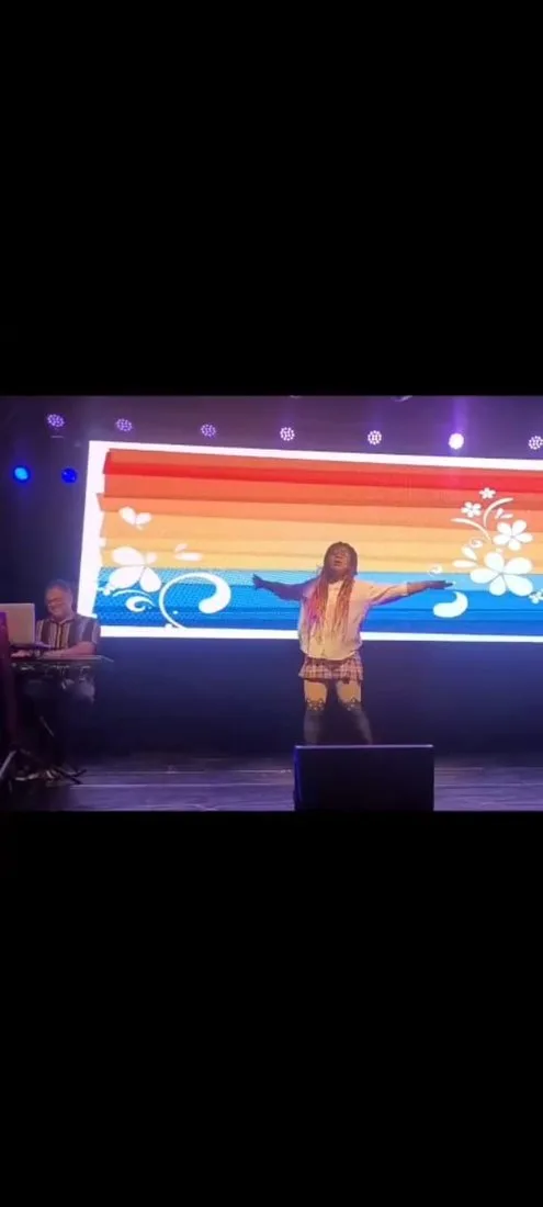Julia Bueno se apresentando com braços abertos no palco